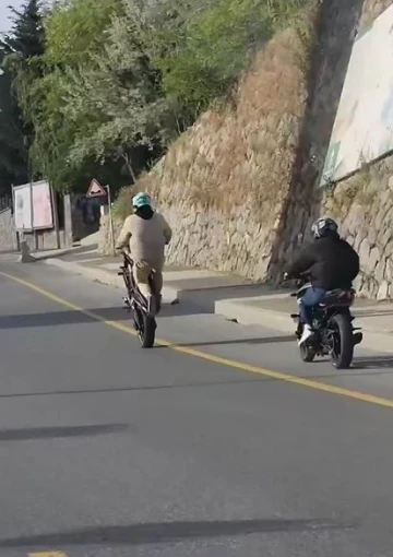 Akrobasi hareketleri yaparak  motosiklet kullanan şahıs kamerada
